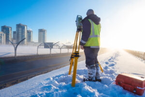 Winter snow and land surveyor overlooking city